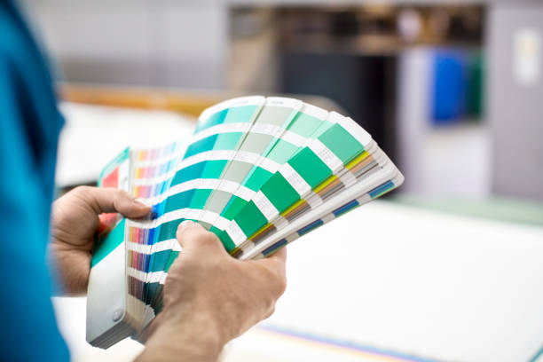 Man hands with colour samples at printing press Close up of man hands with color samples at printing press. Cropped shot male graphic designer with color swatch. graphic designer stock pictures, royalty-free photos & images
