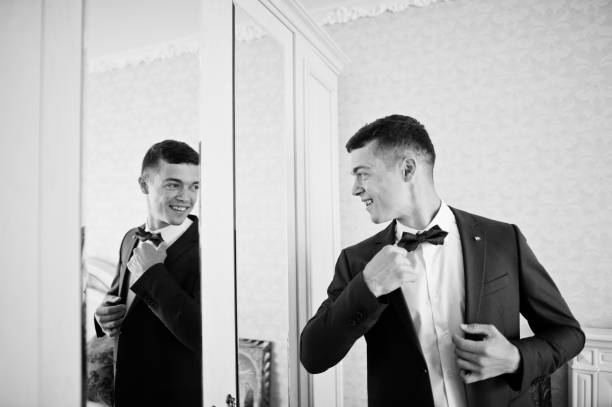 istock Handsome groom dressing up and getting ready for his wedding in the room. 695470030