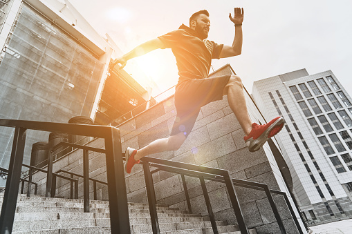 Full length of handsome young man in sport clothing jumping while exercising outside