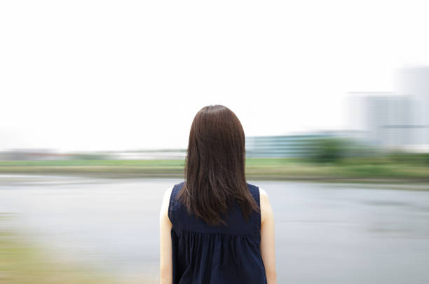 Young woman standing by the river. Blurred background.