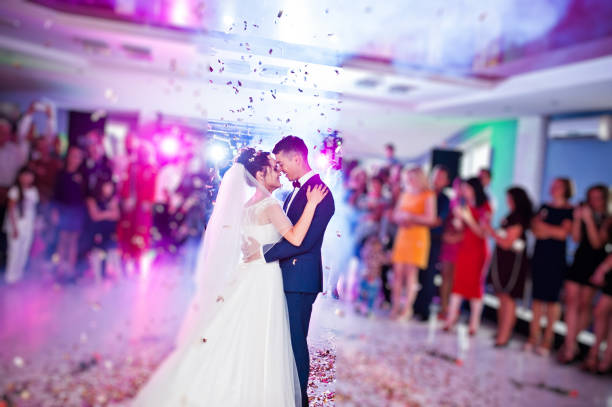 conmovedor y emotivo primer baile de la pareja en su boda con confeti y luces de colores en el fondo. - novio participación en la boda fotografías e imágenes de stock