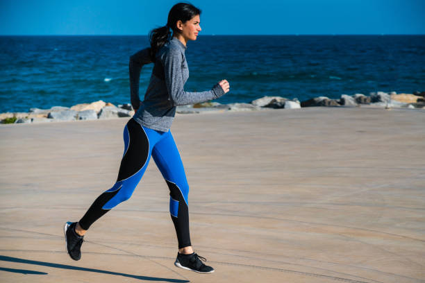 istock Young woman jogging by the sea 695473986