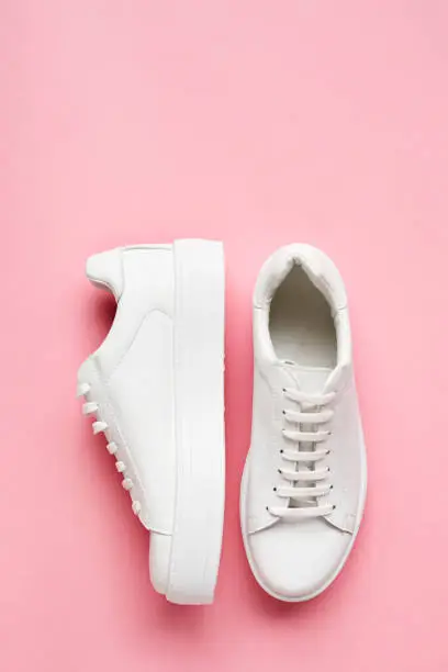 Photo of Overhead Shot Of White Sneakers On Pink Background