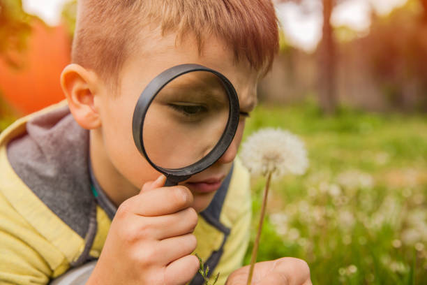 istock Child Exploring the Outdoors With Magnifying Glass 695479982