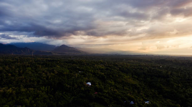 Aerial photo from airplane cockpit of a beautiful outdoors scenery with dramatic, white clouds with sunset rays over silhouette of mountains. Perfect background for website. Wonderful nature landscape