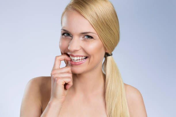 istock Young blond woman biting finger smiling 695484698