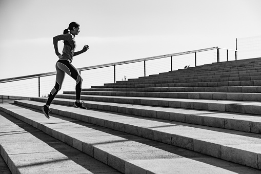 Young athlete woman jogging on stairs outdoors.