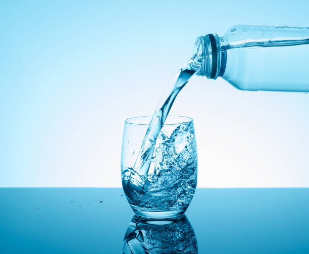 istock Bottle with creative splashing water in the glass 695495464