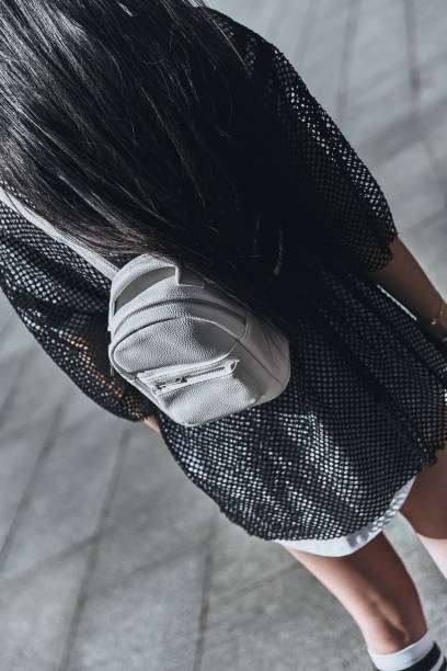 Close-up rear view of young woman carrying a backpack while standing outdoors