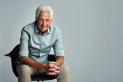 Shot of a senior man sitting against a gray background