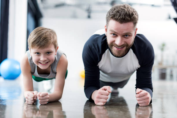 istock Man and boy doing plank exercise at fitness center 695502696