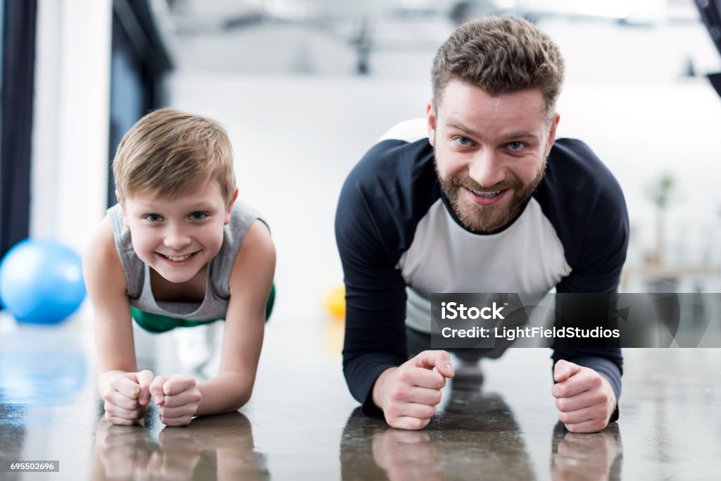 Man and boy doing plank exercise at fitness center Coach Stock Photo