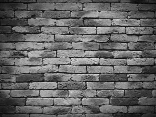 istock Vignetting Weathered texture of stained old black and white brick wall background, grungy rusty blocks of stone work 695502904