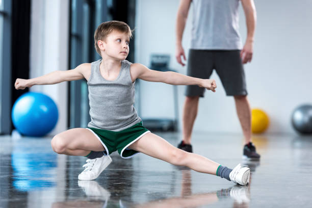 istock Coach controlling boy that doing stretching exercise at fitness center 695503144
