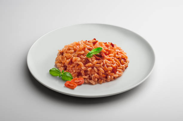 Risotto dish with dried tomatoes and basil Risotto dish with dried tomatoes and basil isolated on white table tomato rice stock pictures, royalty-free photos & images