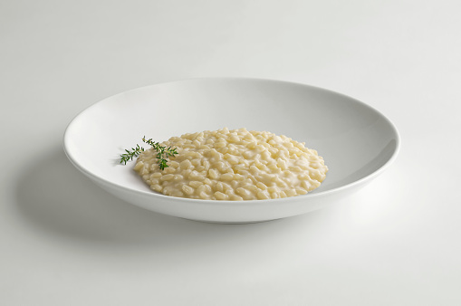 Bowl of Cheese risotto with thyme isolated on white table