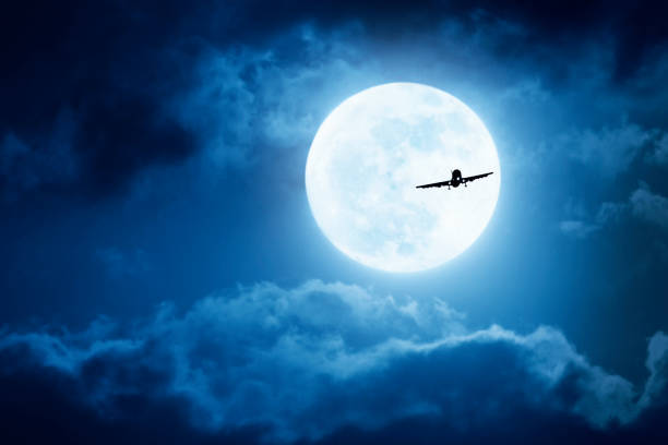istock Dramatic Nighttime Sky With Large Full Blue Moon and Commercial Aircraft 695506360
