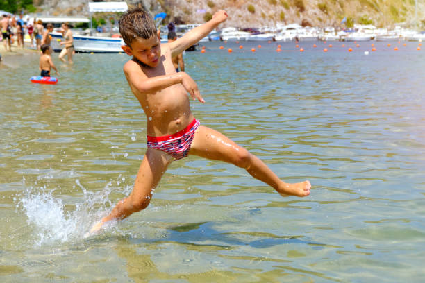 Summer vacations, kids playing and jumping into water at sea
