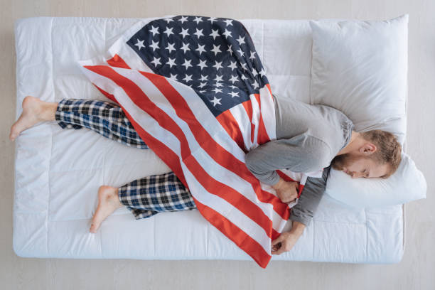 istock Nice patriotic man sleeping with American flag 695513322