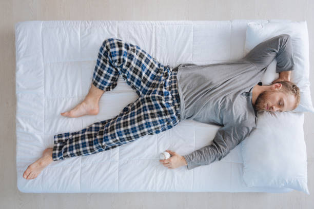 Peaceful nice man having a tennis ball in his hands Time to play. Peaceful nice well built man having a tennis ball in his hands and preparing to play tennis while being in his dream man sleeping top view stock pictures, royalty-free photos & images