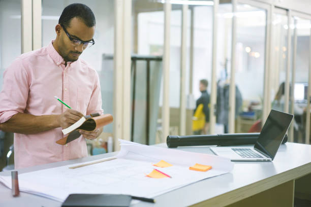 istock Young teacher and student noting ideas into personal organizer while creating graphic blueprint 695518972
