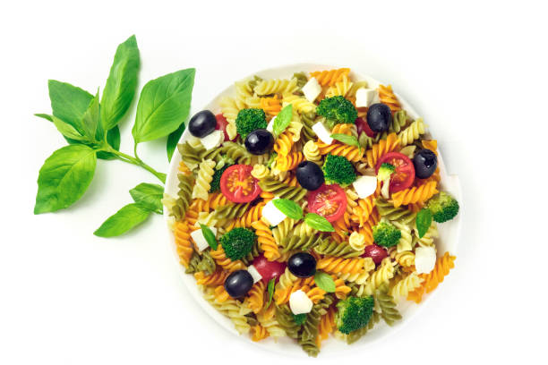 Plate of pasta salad with basil leaves on white A photo of a plate of pasta salad with basil leaves, shot from above on a white background with a place for text spinach pasta stock pictures, royalty-free photos & images