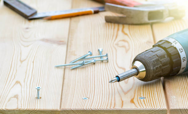 istock Screw and electric screwdriver on a wooden board 695533384