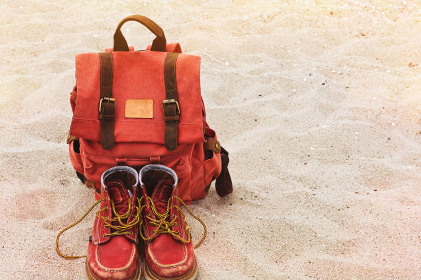 istock Vintage backpack and worn boots on the sand beach 695535132