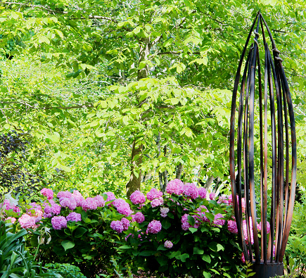 Copper sculpture with pink hydrangeas in the background.