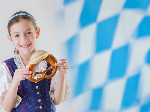 Bavarian little girl in traditional dress Dirndl and pretzel