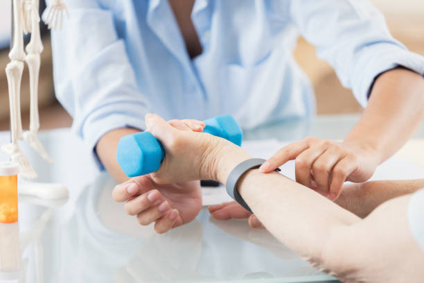 istock Unrecognizable physical therapist helps woman with hand weights 695573256