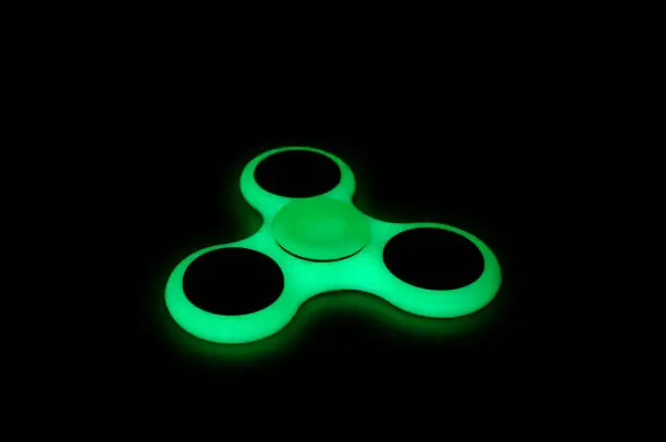 Photo of Glow in the dark fidget spinner on black background