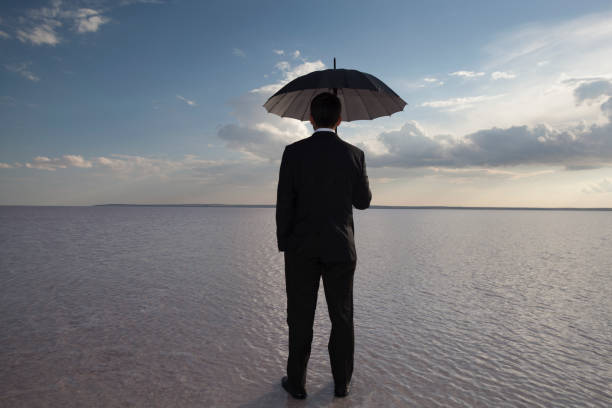 istock Man in black suit with a black umbrella On Salt Lake 695580458