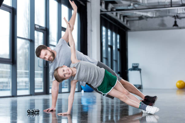 istock Man and boy doing plank exercise at fitness center 695585462