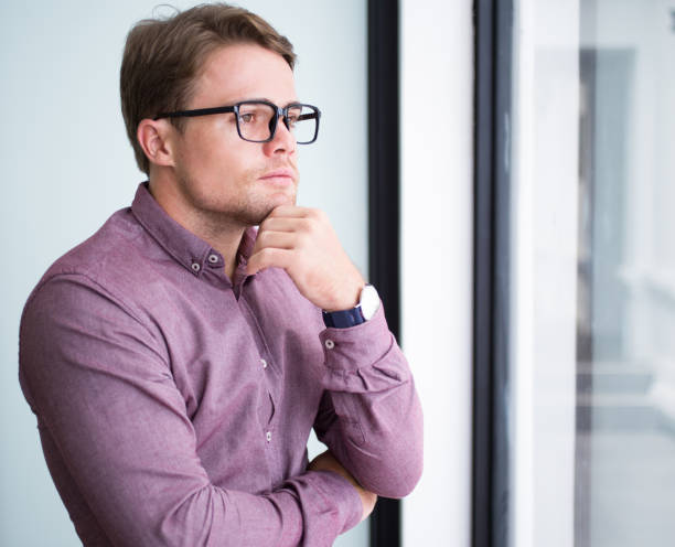 istock Pensive young businessman standing touching chin 695588866