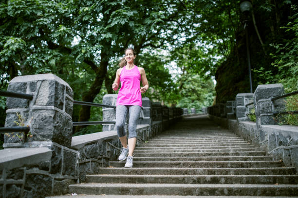 An adult woman training on a large set of outdoor steps, running and employing other stairway exercise variations.