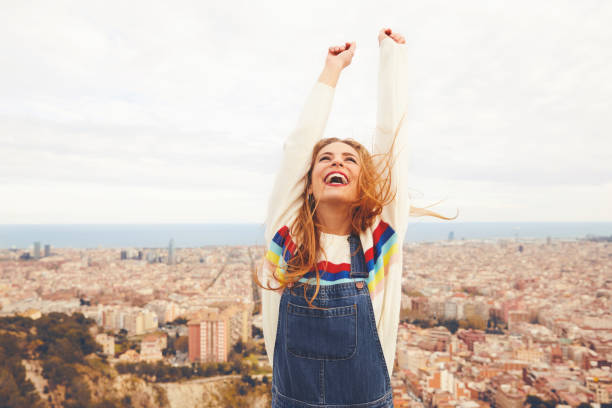 Happy woman with arms raised against cityscape stock photo