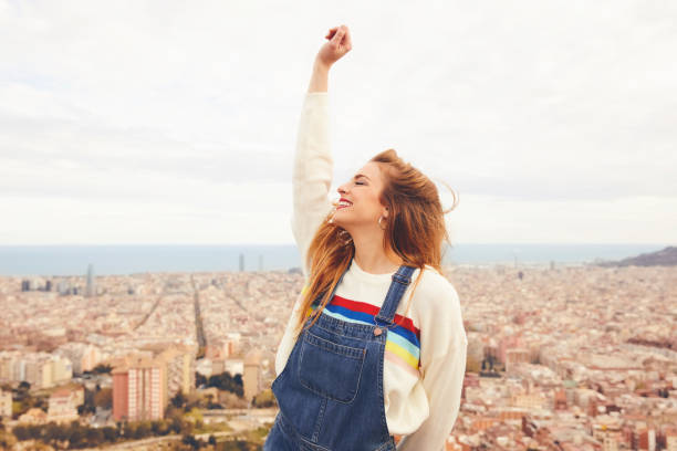 istock Cheerful woman with hand raised against cityscape 695593410