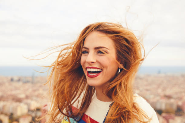 веселая женщина с вясными волосами против городского пейзажа - red hair стоковые фото и изображения