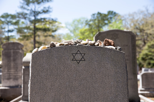 Headstone in a Jewish cemetery with Star of David and memory stones.  Selective focus on the foreground.  Copy space.