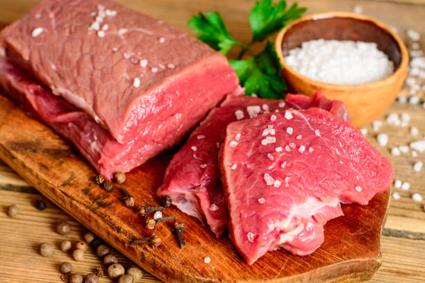 istock Raw beef meat on rustic wooden cutting board. 695597350