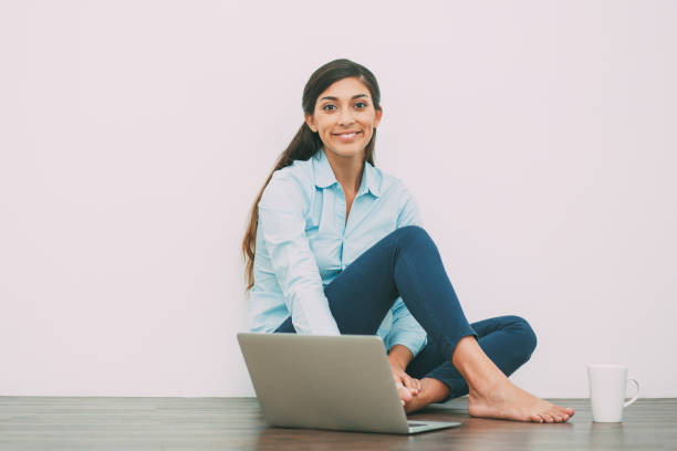istock Smiling Young Woman with Laptop and Tea on Floor 695597542