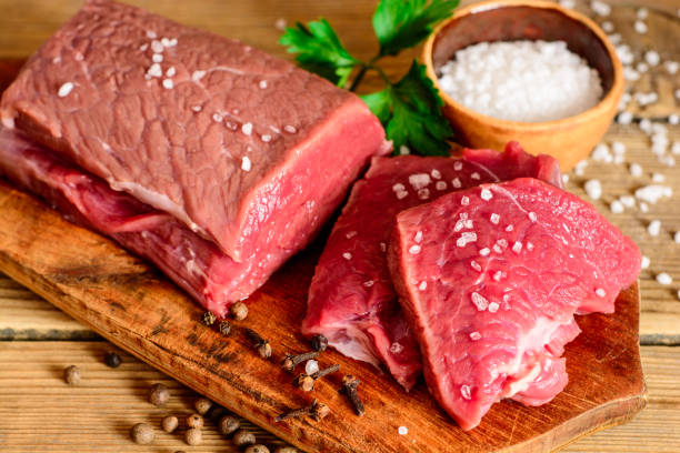 istock Raw beef meat on rustic wooden cutting board. 695597632
