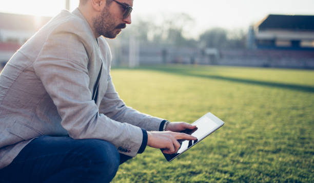 Football manager Manager man crouching on soccer field and using tablet club soccer photos stock pictures, royalty-free photos & images