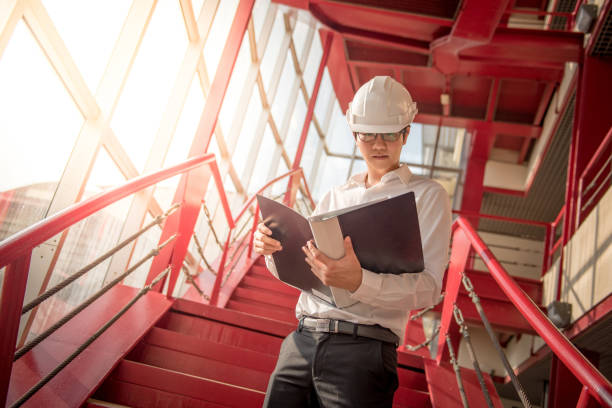 istock Young Asian Engineer holding files at construction site 695605078