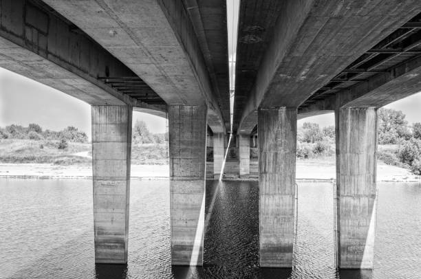 istock Bridge over the river. Architectural lines and concrete poles under the bridge. Black and white. 695605792