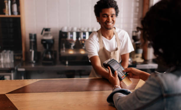 young woman paying by credit card at cafe - coffee serving cafeteria worker checkout counter imagens e fotografias de stock