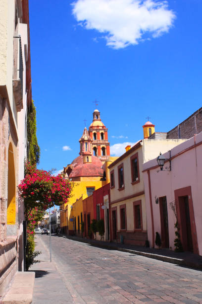 Street with medieval buildings, Queretaro, Mexico Street with historic medieval buildings, flowering bougainvillea and a road from paving stones in Queretaro, Mexico queretaro city stock pictures, royalty-free photos & images