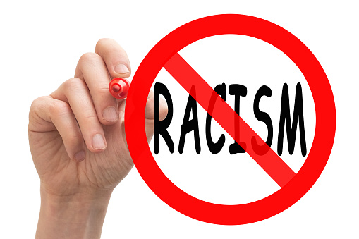 Conceptual image showing a hand drawing stop sign around the word racism.