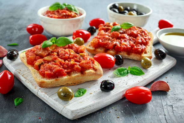 aperitivo italiano crujiente casero bruschetta fresca había coronada con tomate, berenjena, calabacín, pimiento amarillo, ajo y albahaca sobre tablero madera blanco. alimentos saludables - mediterranean cuisine salad olive oil tomato salad fotografías e imágenes de stock